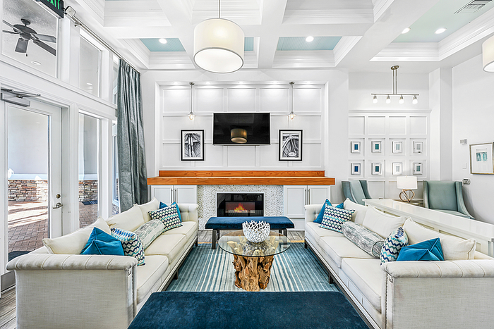 Elegant and spacious clubhouse showcasing a modern fireplace, luxurious couches with vibrant cushions, and stylish decor in a bright, airy setting.