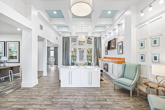 Elegant clubhouse with high ceilings, modern decor, and ample natural light, featuring a cozy seating area and sleek wooden floors.