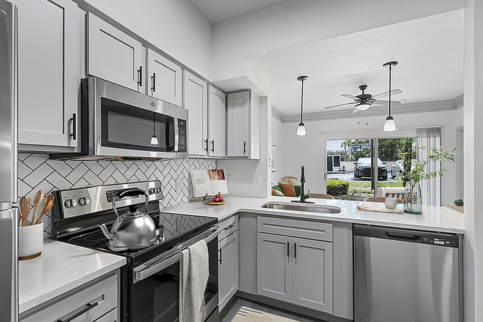 Contemporary kitchen with sleek stainless steel appliances, elegant white cabinetry, and expansive windows offering a serene garden view.