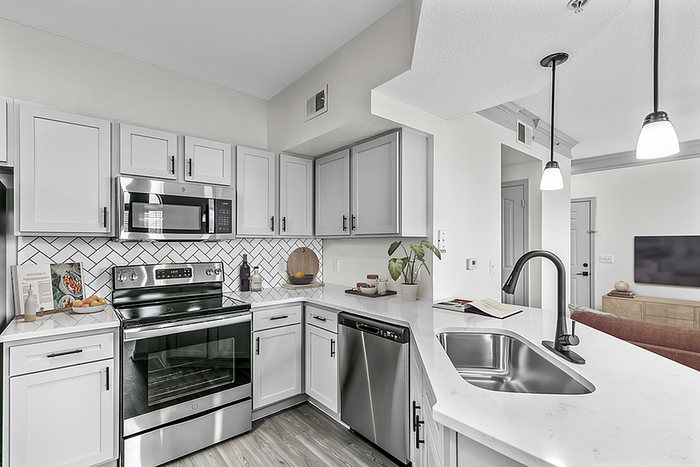 Modern kitchen with sleek white cabinetry, stainless steel appliances, and elegant pendant lighting over a spacious marble countertop.