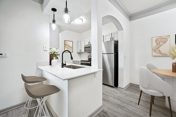 Sleek modern kitchen and dining area with stylish lighting, stainless steel appliances, and elegant countertops creating a warm and inviting atmosphere.