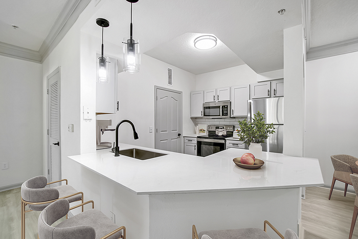 Modern kitchen with sleek white countertops, stainless steel appliances, and stylish pendant lighting, creating a bright and inviting cooking space.