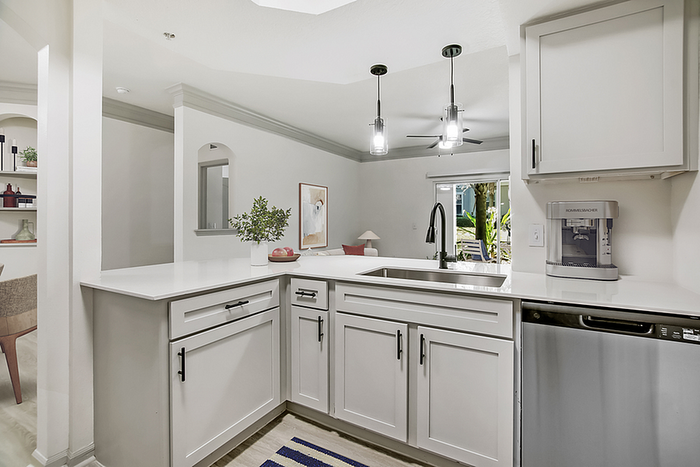 Elegant modern kitchen with sleek white cabinetry, stylish pendant lights, and stainless steel appliances offering a perfect blend of style and functionality.