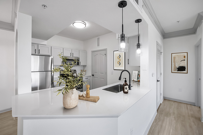 Modern kitchen with sleek stainless steel appliances, elegant white cabinetry, and stylish pendant lighting.