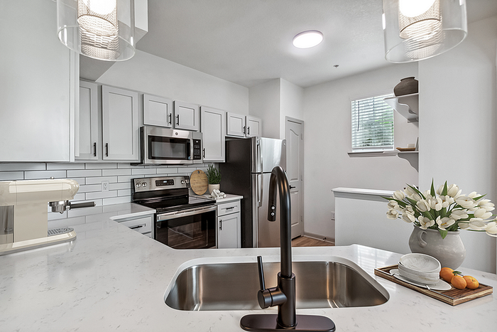 Modern kitchen with sleek white cabinets, stainless steel appliances, and elegant lighting, perfect for culinary enthusiasts.