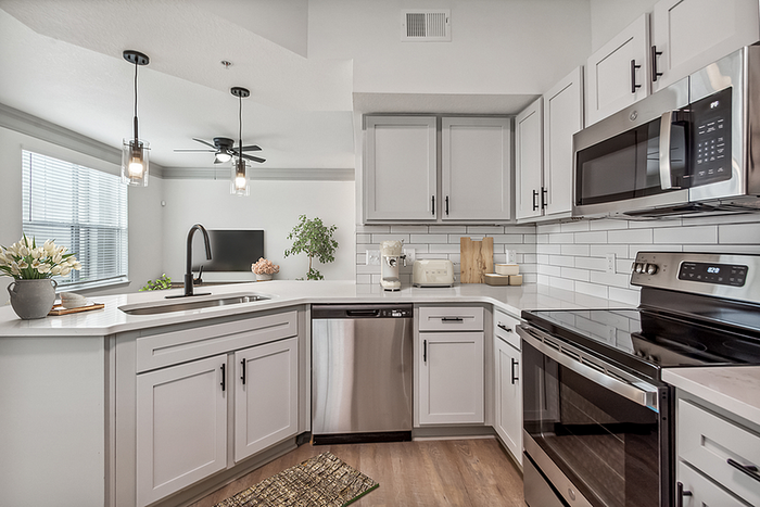 Modern kitchen featuring sleek stainless steel appliances, elegant white cabinetry, and contemporary pendant lighting for a stylish cooking experience.