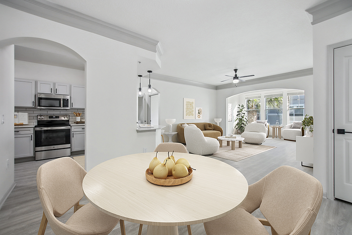 Modern apartment interior with open-concept living and dining area, featuring elegant gray kitchen cabinetry, stylish dining chairs, and a bright living room with large windows.