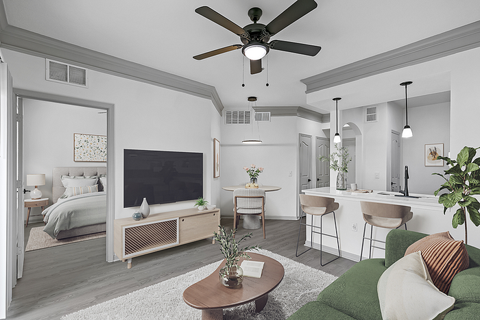 Chic modern living space featuring an open-plan kitchen, cozy living room with green sofa, and stylish bedroom visible through open door.