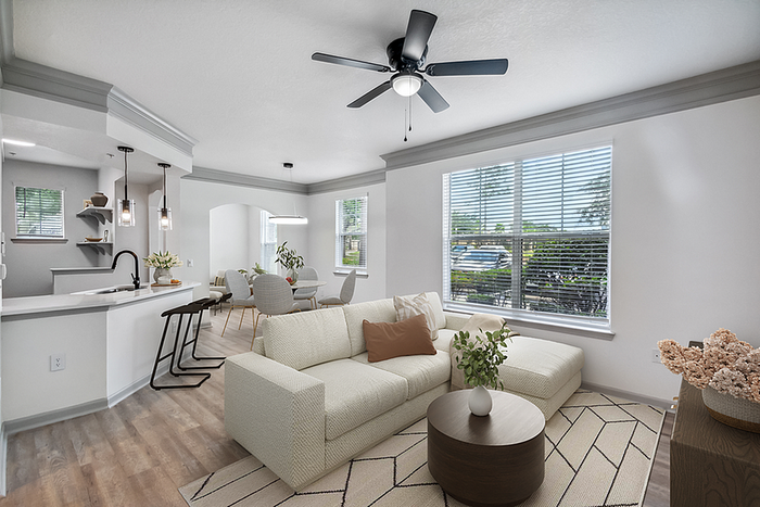 Bright and inviting living room with modern open-plan kitchen, cozy seating, stylish dining area, and large sunlit windows.