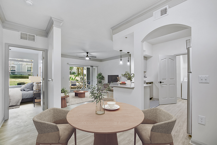 Bright and spacious apartment interior showcasing a modern open-concept living area with dining space, stylish kitchen, and cozy bedroom view.