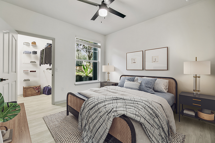 Bright and airy bedroom with modern decor, featuring a cozy bed, stylish lamps, and a spacious walk-in closet, enhanced by natural light from a large window.