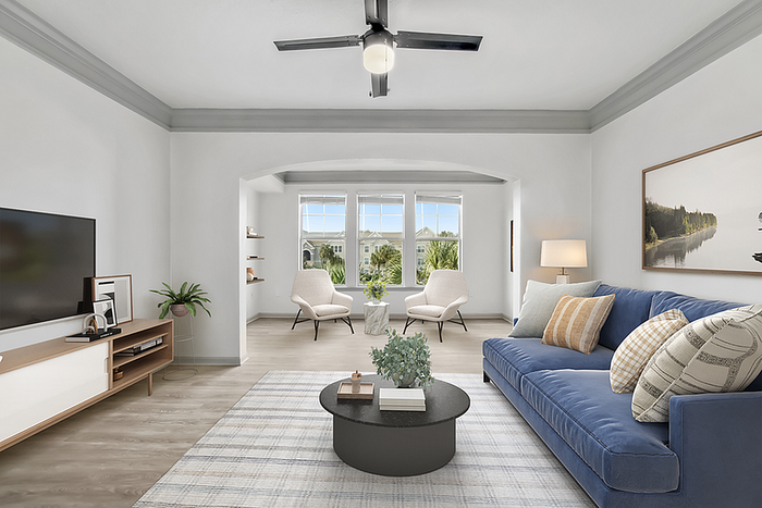 Bright, inviting living room with stylish blue sofa, modern decor, and ample natural light from large windows.