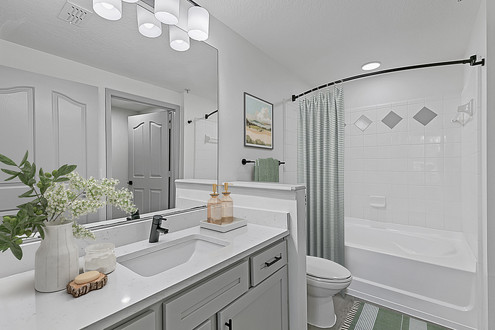Elegant modern bathroom with white vanity, stylish fixtures, and inviting bathtub surrounded by chic decor elements.