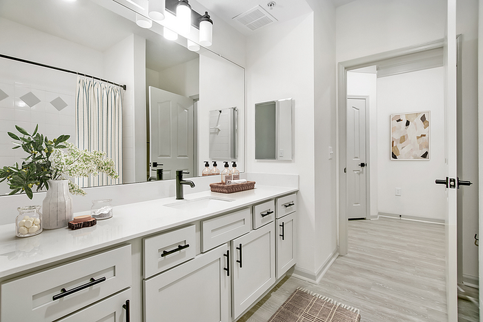 Elegant bathroom featuring double sinks, sleek white cabinetry, and a modern aesthetic with natural accents.