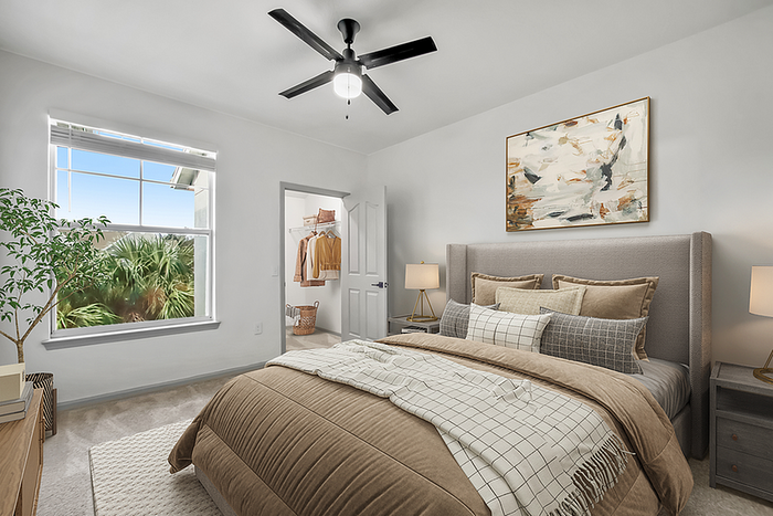 Bright and inviting bedroom with modern decor, cozy bedding, and large window with a scenic view of greenery.