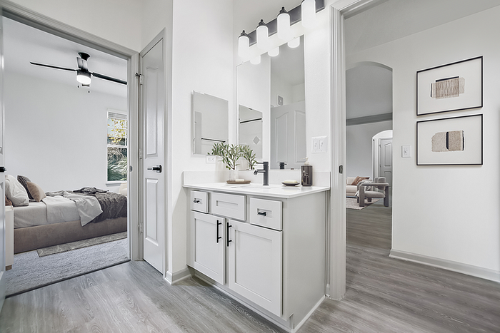 Bright and elegant bedroom suite with a modern vanity area, offering seamless flow into the cozy living space.