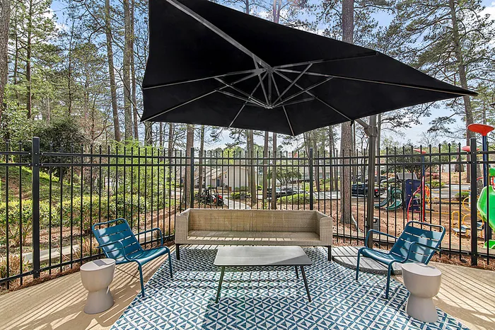 Inviting outdoor patio with chic seating, modern umbrella, and scenic wooded views&mdash;perfect for relaxation and entertaining.