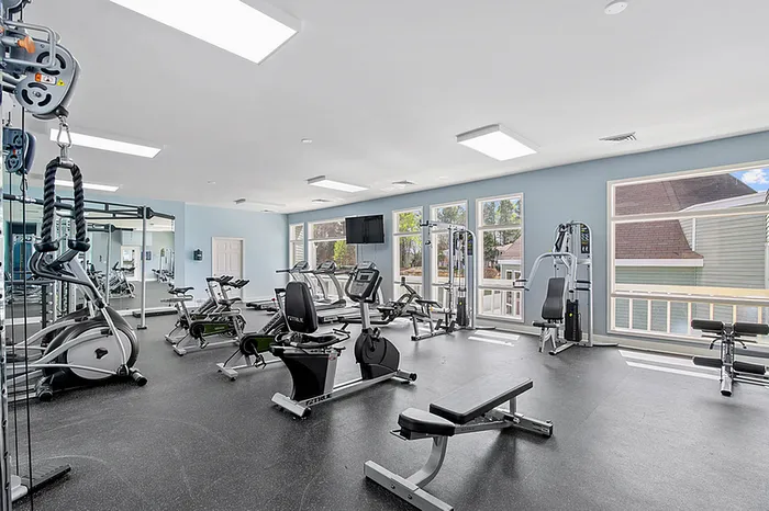 Well-equipped fitness center with modern exercise machines, ample natural light, and spacious layout.
