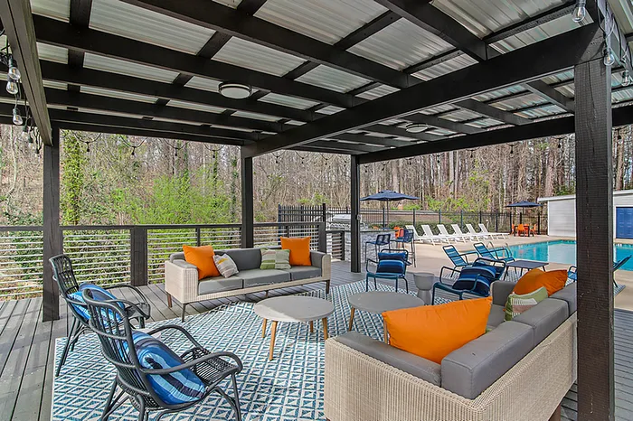 Inviting outdoor lounge area with vibrant cushions, cozy seating, and a serene poolside view under a modern pergola.