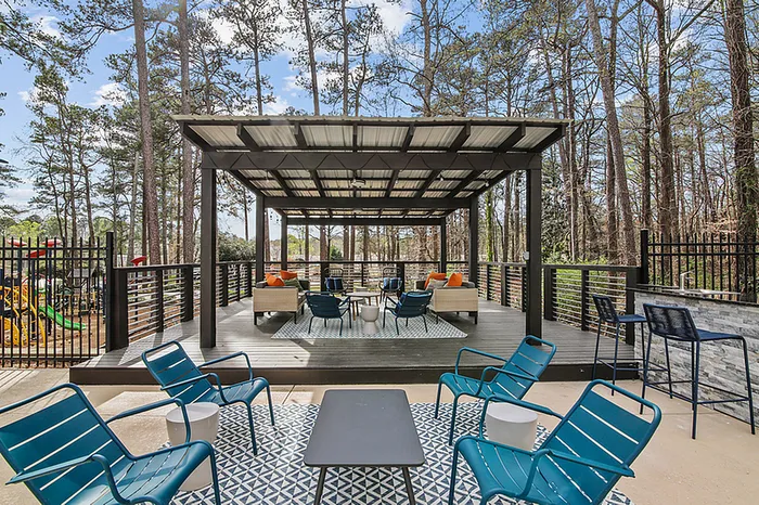Chic outdoor patio featuring modern seating, vibrant decor, and a stunning view of lush trees, ideal for relaxation and entertaining.