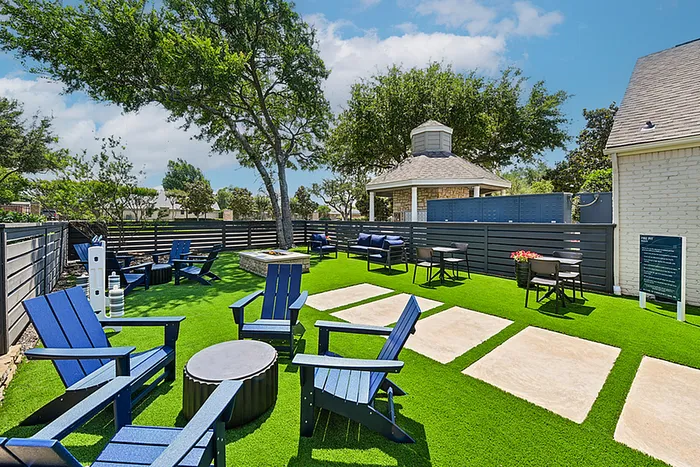Charming outdoor lounge area with vibrant green lawn, stylish blue seating, and a cozy gazebo, perfect for relaxation and social gatherings.