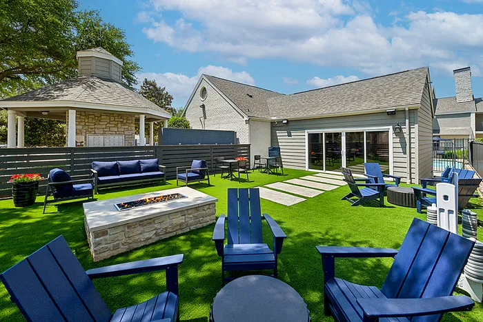 Chic outdoor lounge with vibrant green lawn, cozy fire pit, and elegant stone gazebo for perfect relaxation.