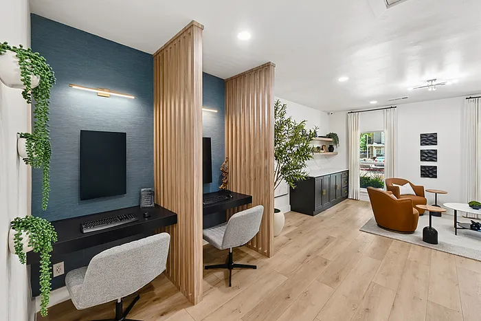 Modern co-working lounge with sleek workstations, stylish seating area, and vibrant greenery, offering a chic and productive environment.