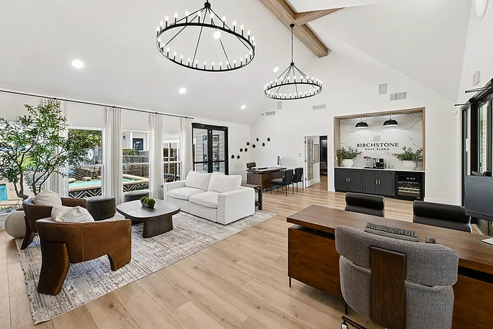 Luxurious modern leasing office with stylish seating, elegant lighting, and large windows overlooking the pool area at Birchstone West Plano.
