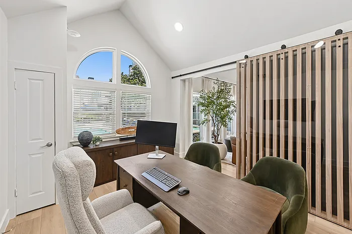 Bright and elegant leasing office with modern desk, soft armchair, and large arched window providing natural light.