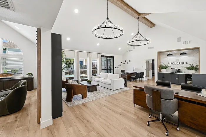 Luxurious open-concept leasing office featuring modern furnishings, elegant chandeliers, and expansive windows for abundant natural light.