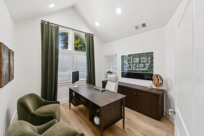 Elegant leasing office with high ceilings, large arched window with greenery view, stylish dark wood desk, and cozy velvet chairs.