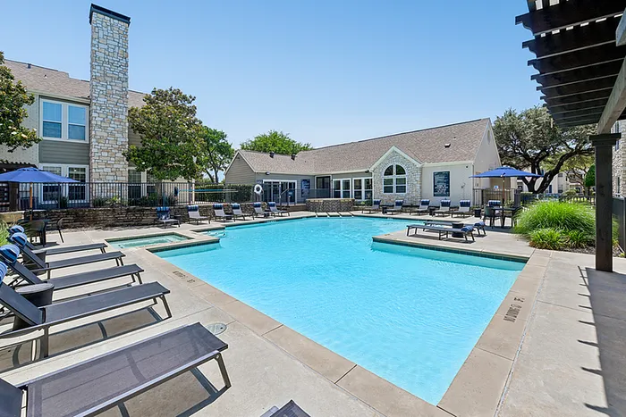 Inviting outdoor pool area with stylish lounge chairs, surrounded by lush greenery and elegant architecture perfect for relaxation.