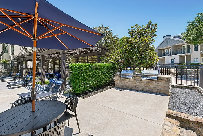 Inviting outdoor area with modern BBQ grills, cozy seating under shaded pergolas, and vibrant greenery, perfect for relaxation and entertaining.