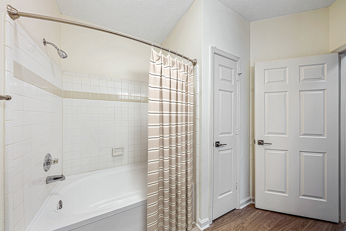 Elegant bathroom with modern amenities, featuring a pristine white bathtub, stylish shower curtain, and minimalist design.