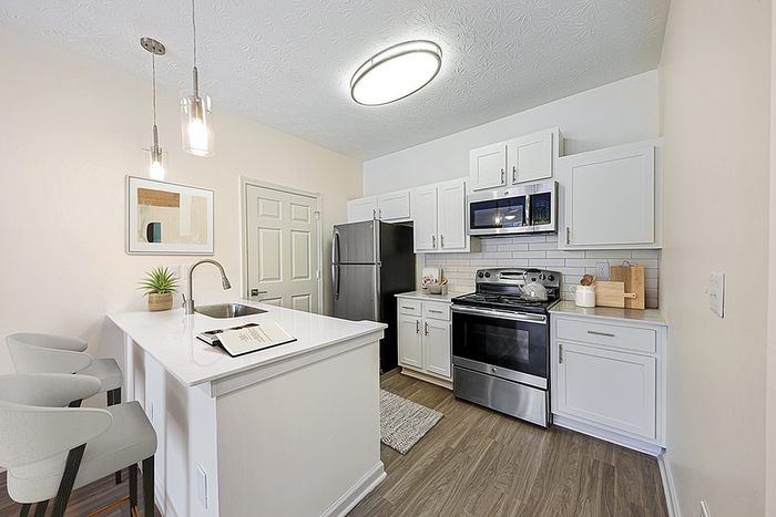 Modern kitchen with sleek white cabinetry, stainless steel appliances, and a stylish breakfast bar with pendant lighting.