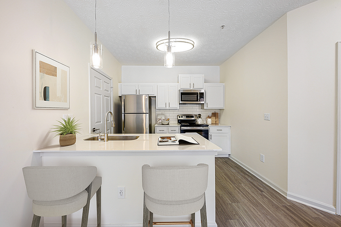 Modern kitchen with stainless steel appliances, sleek white cabinetry, and stylish pendant lighting over a chic breakfast bar.