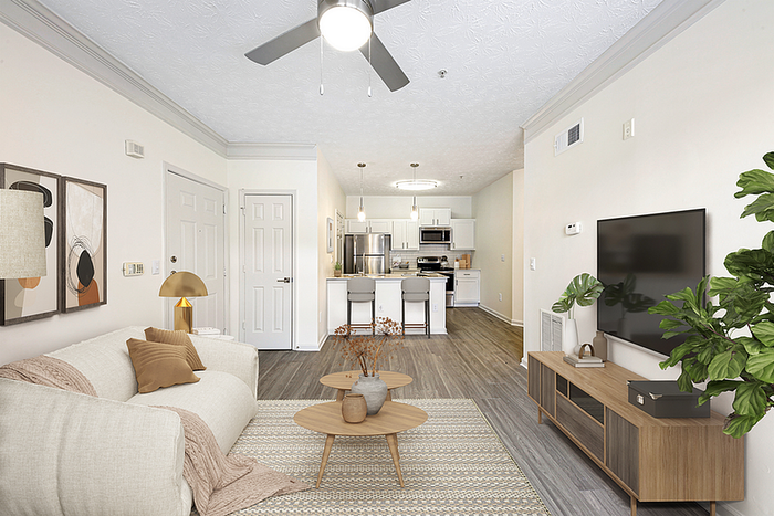 Chic modern living room with elegant decor, open-concept layout leading to a sleek kitchen, featuring hardwood floors and bright natural lighting.