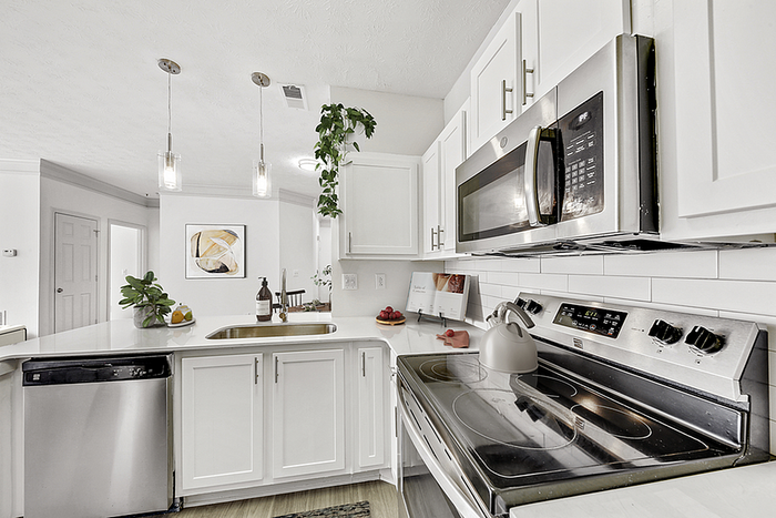 Modern kitchen with sleek stainless steel appliances, elegant white cabinetry, and stylish pendant lighting for a contemporary touch.