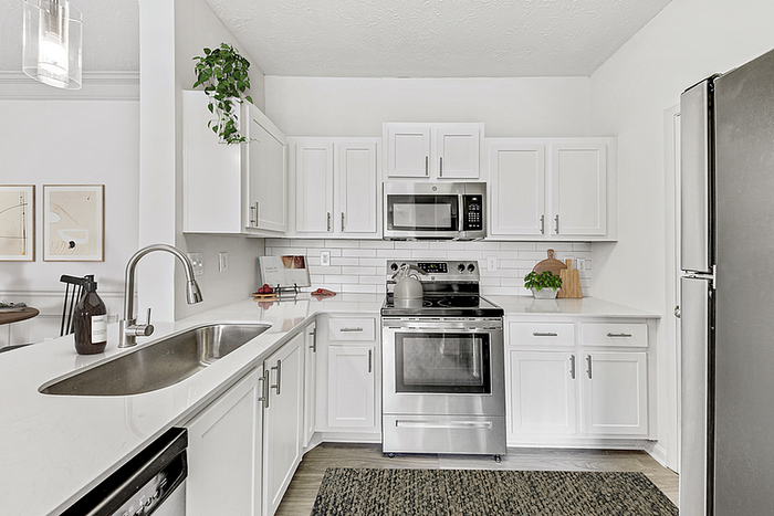Contemporary kitchen with sleek white cabinetry, stainless steel appliances, and elegant subway tile backsplash.