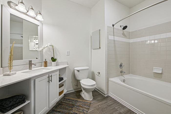Elegant bathroom with modern fixtures, featuring a stylish vanity, tiled bathtub, and ambient lighting for a serene atmosphere.