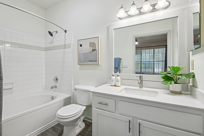Elegant bathroom with modern fixtures, featuring a spacious bathtub, stylish vanity mirror, and sleek tile design.