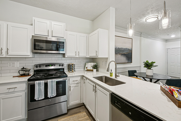 Modern kitchen with sleek white cabinetry, stainless steel appliances, and elegant pendant lighting next to a cozy dining area.