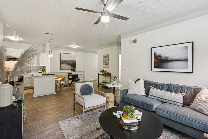 Chic open-concept living room and kitchen with modern decor, featuring sleek wood flooring, a cozy seating area, and stylish artwork.