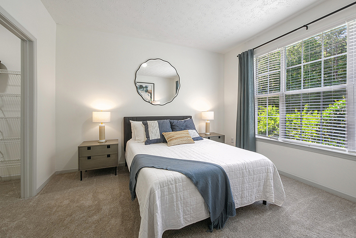 Bright and inviting bedroom with plush carpeting, modern decor, large window with scenic view, and ambient lighting.