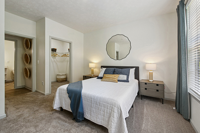 Inviting bedroom with modern decor, featuring a comfortable bed, stylish nightstands, and ample natural light from large windows.