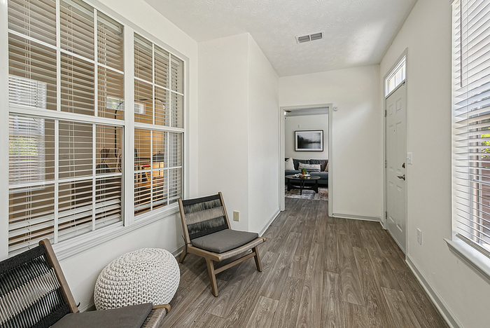 Bright and inviting hallway with modern wood flooring, leading to a cozy living space with natural lighting.