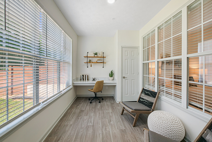 Bright and inviting home office space with large windows, stylish desk, and comfortable seating, ideal for productivity and comfort.