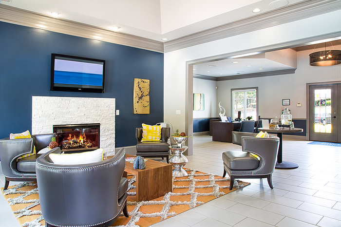 Chic apartment lounge with modern fireplace, elegant grey chairs, and vibrant decor.