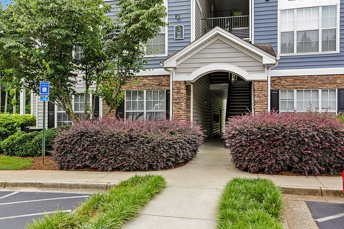 Charming apartment entrance with inviting greenery and classic stone accents, perfect for a serene living experience.