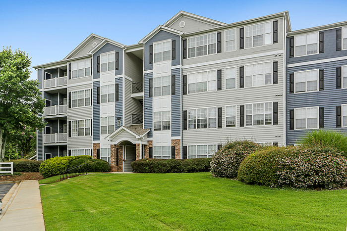 Elegant multi-story apartment complex with modern architecture and lush green landscaping, ideal for comfortable urban living.
